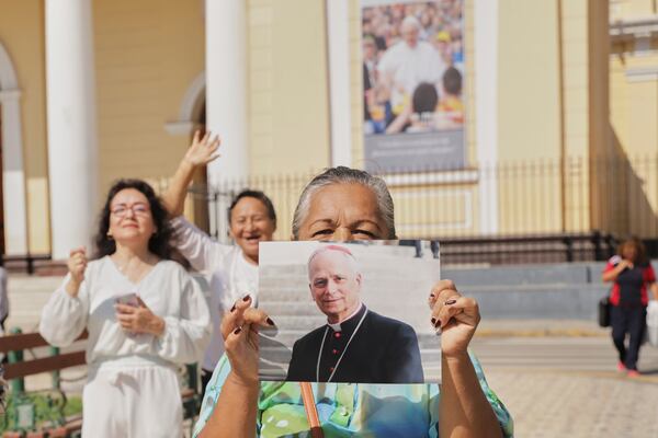Faithful hold a photo of Bishop Robert Prevost, who was elected Pope Leo XIV, in front of the Cathedral of Chiclayo, Peru, Tuesday, May 8, 2025, where he served as bishop for several years, (AP Photo/Manuel Medina)