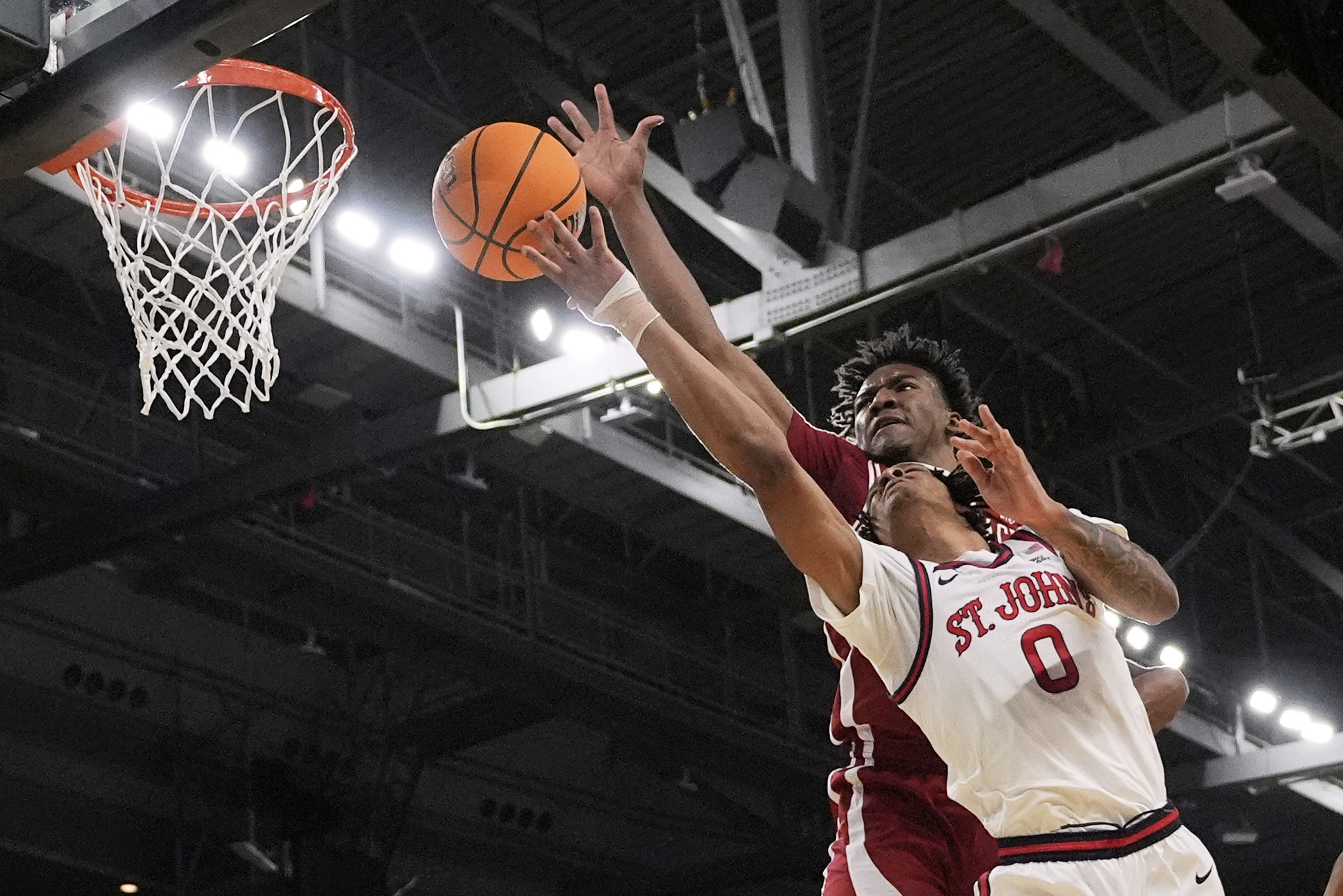 Arkansas forward Karter Knox, rear, reaches over St. John's guard Aaron Scott (0) to block a shot during the first half in the second round of the NCAA college basketball tournament, Saturday, March 22, 2025, in Providence, R.I. (AP Photo/Charles Krupa)