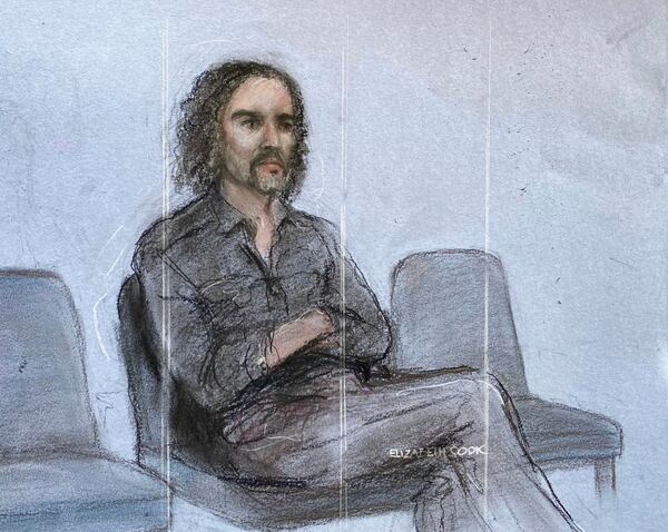 This court artist drawing by Elizabeth Cook shows Russell Brand appearing in the dock at Westminster Magistrates' Court, London, Friday, May 2, 2025, where he is charged with with one count each of rape, indecent assault and oral rape, as well as two counts of sexual assault, relating to four separate women. (Elizabeth Cook/PA via AP)
