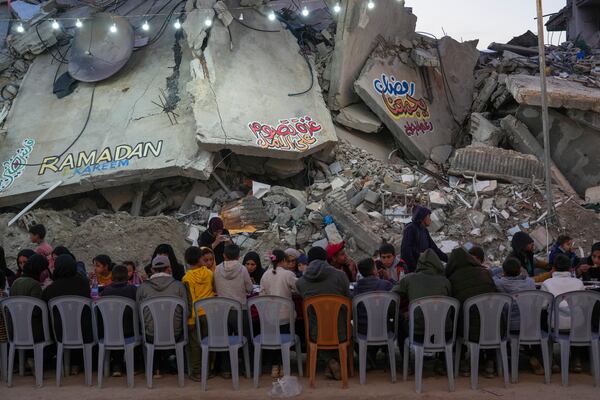 Palestinians sit at a large table surrounded by the rubble of destroyed homes and buildings as they gather for iftar, the fast-breaking meal, on the first day of Ramadan in Rafah, southern Gaza Strip, Saturday, March 1, 2025 (AP Photo/Abdel Kareem Hana)