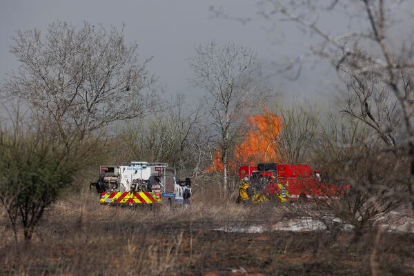 Firefighters work to put out a brush fire in a field along Southton Road, near Interstate 37, on the far southeast side of San Antonio, Tuesday, March 4, 2025. (Sam Owens/The San Antonio Express-News via AP)