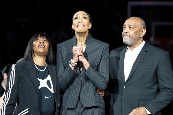 A'ja Wilson, center, stands with her parents Eva and Roscoe Wilson as they watch her number be retired during a ceremony before an NCAA college basketball game between South Carolina and Auburn in Columbia, S.C., Sunday, Feb. 2, 2025. (AP Photo/Nell Redmond)