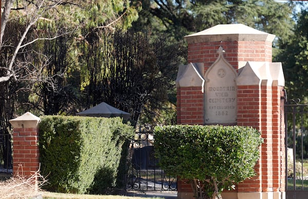 Singed brush is seen at right near the entrance gate to the closed Mountain View Cemetery, Tuesday, Jan. 14, 2025, in Altadena, Calif. (AP Photo/Chris Pizzello)