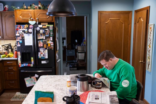 Paul Safarik, 32, reads the newspaper with a cup of coffee by his side on Wednesday, Feb. 12, 2025, in Lincoln, Neb. (AP Photo/Rebecca S. Gratz)