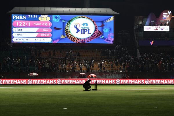 A worker removes the equipment placed next to the stumps after the authorities asked to evacuate the stadium during the Indian Premier League cricket match between Punjab Kings and Delhi Capitals at Himachal Pradesh Cricket Association Stadium in Dharamshala, India, Thursday, May 8, 2025. (AP Photo/Ashwini Bhatia)