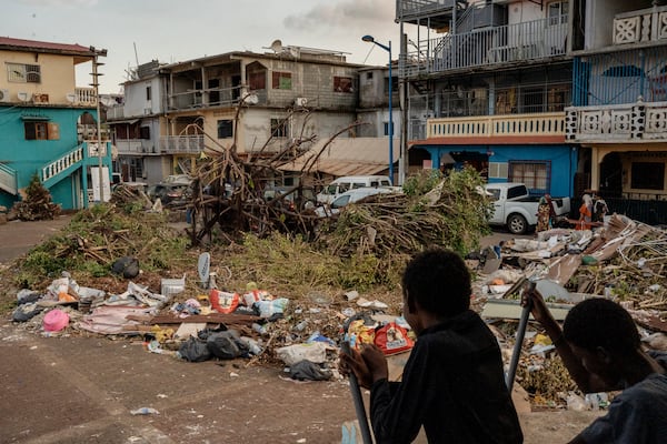 Kids play on a public square filled with garbage and debris, Thursday, Dec. 19, 2024, in Mamoudzou, Mayotte. (AP Photo/Adrienne Surprenant)