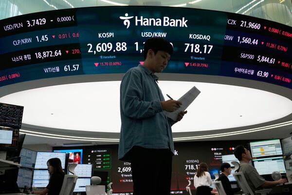 A currency trader works near a screen showing the Korea Composite Stock Price Index (KOSPI), top center left, and the foreign exchange rate between U.S. dollar and South Korean won, top center, at the foreign exchange dealing room of the KEB Hana Bank headquarters in Seoul, South Korea, Thursday, May 22, 2025. (AP Photo/Ahn Young-joon)