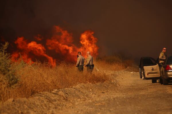 County Sheriff officers monitor flames caused by the Hughes Fire in Castaic, Calf., Wednesday, Jan. 22, 2025. (AP Photo/Ethan Swope)