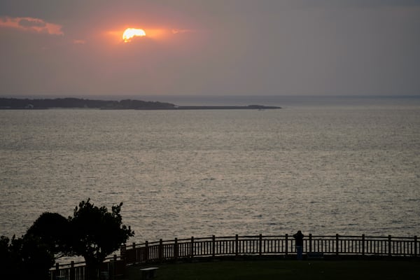 A person watches the sunrise from the Chinen Misaki Park in Nanjo, on the main island of the Okinawa archipelago, southern Japan, Wednesday, Feb. 19, 2025. (AP Photo/Hiro Komae)