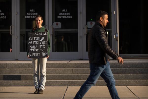 Chloe Kienzle of Arlington, Va., holds a sign as she stands outside the headquarters of the U.S. Department of Eduction, which were ordered closed for the day for what officials described as security reasons amid large-scale layoffs, Wednesday, March 12, 2025, in Washington. (AP Photo/Mark Schiefelbein)