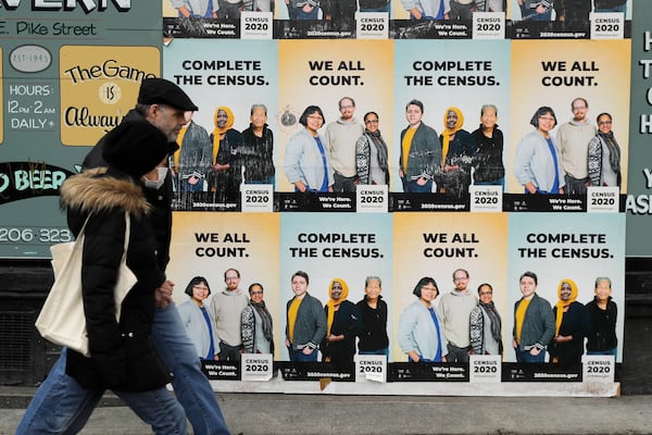 FILE - People walk past posters encouraging participation in the 2020 Census in Seattle's Capitol Hill neighborhood, April 1, 2020.(AP Photo/Ted S. Warren, File)