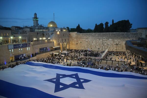 Members of Jewish youth movements unfurl a giant Israeli flag on the eve of Jerusalem Day an Israeli holiday celebrating the capture of the Old City during the 1967 Mideast war, next to the Western Wall in the Old City of Jerusalem, Sunday, May 25, 2025. (AP Photo/Ohad Zwigenberg)