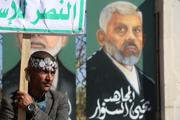 A Houthi supporter raises a banner in front of a billboard of Hamas leader Yahya Sinwar, who killed by Israeli troops in Gaza last year, during an anti-Israel rally in Sanaa, Yemen, Friday, Jan. 17, 2025. (AP Photo/Osamah Abdulrahman)