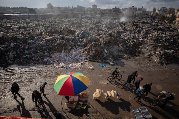 Palestinians walk past a pile of burning garbage, as there is no refuse collection in the city and people are disposing of their rubbish in the streets, in Gaza City, Wednesday, Feb. 12, 2025. (AP Photo/Jehad Alshrafi)