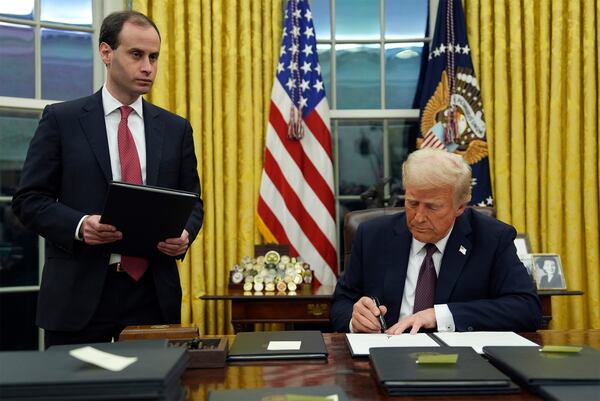 President Donald Trump signs an executive order to create the Department of Government Efficiency (DOGE) in the Oval Office of the White House, Monday, Jan. 20, 2025, in Washington, as White House staff secretary Will Scharf watches. (AP Photo/Evan Vucci)