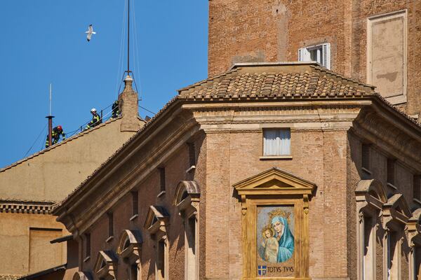 Firefighters place the chimney on the roof of the Sistine Chapel, where cardinals will gather to elect the new pope, at the Vatican, Friday, May 2, 2025. (AP Photo/Bernat Armangue)