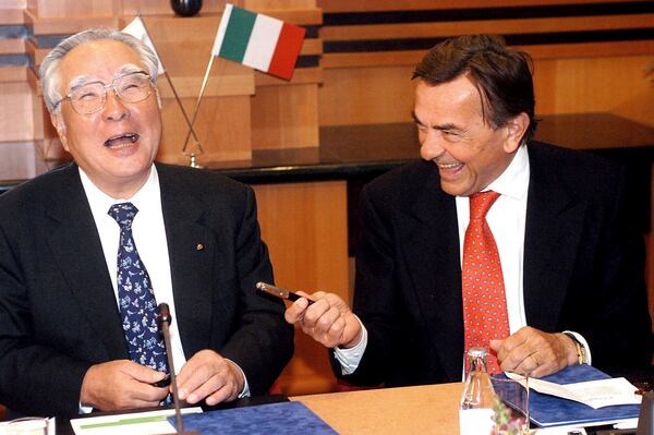 FILE - Chairman and CEO of the Japanese carmaker Suzuki Motor Corp., Osamu Suzuki, left, and President and CEO of Fiat Auto S.p.A. of Italy, Giancarlo Boschetti, share a laugh before they signed an agreement on jointly developing and producing a new sport utility vehicle in a hotel in Budapest, Hungary, April 10, 2003. (Tamas Kovacs/MTI via AP, File)