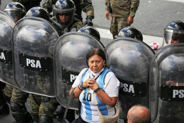 A woman stands in front of riot police during a protest by soccer fans and retirees demanding higher pensions and opposing austerity measures implemented by Javier Milei's government in Buenos Aires, Argentina, Wednesday, March 12, 2025. (AP Photo/Natacha Pisarenko)