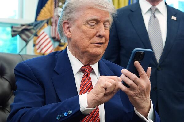 President Donald Trump silences his mobile phone which rang two times as he was speaking to reporters after signing executive orders regarding nuclear energy in the Oval Office of the White House, Friday, May 23, 2025, in Washington. (AP Photo/Evan Vucci)