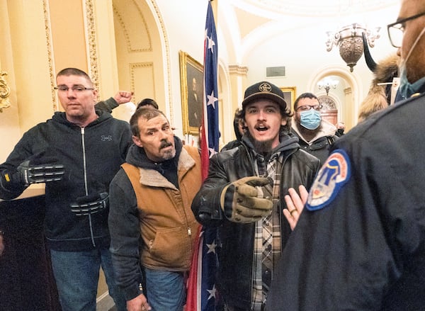 FILE - Violent protesters loyal to President Donald Trump, including Kevin Seefried, center, holding a Confederate battle flag, are confronted by U.S. Capitol Police officers outside the Senate Chamber inside the Capitol, Jan. 6, 2021 in Washington. (AP Photo/Manuel Balce Ceneta, File)