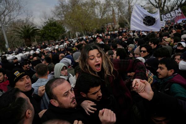 A woman is helped to leave during scuffles between anti riot police officers and people who protest the arrest of Istanbul Mayor Ekrem Imamoglu, in Istanbul, Turkey, Thursday, March 20, 2025. (AP Photo/Khalil Hamra)