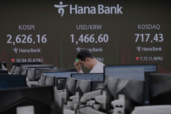 A currency trader reacts near a screen showing the Korea Composite Stock Price Index (KOSPI), top left, and the foreign exchange rate between U.S. dollar and South Korean won, top center, at the foreign exchange dealing room of the KEB Hana Bank headquarters in Seoul, South Korea, Friday, March 21, 2025. (AP Photo/Ahn Young-joon)