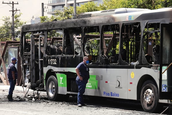 Police inspect a bus that caught fire after a small aircraft crashed on an avenue in Sao Paulo, Friday, Feb. 7, 2025. (AP Photo/Ettore Chiereguini)