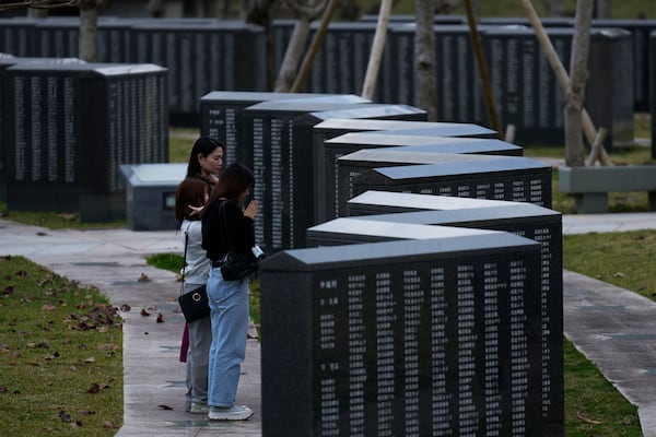 Kanai from Yokohama (only her last name provided on condition of anonymity), back, and her friends pray in front of a Cornerstone of Peace monument with the name of Kanai's grandfather imprinted, created in memory of those who died in the Battle of Okinawa, at the Peace Memorial Park in Itoman, on the main island of the Okinawa archipelago, southern Japan, Wednesday, Feb. 19, 2025. (AP Photo/Hiro Komae)