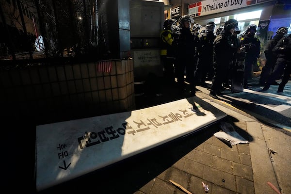 Police officers stand outside of the Seoul Western District Court after supporters of impeached South Korean President Yoon Suk Yeol broke into the court in Seoul, South Korea, Sunday, Jan. 19, 2025. The letters read "The Seoul Western District Court." (AP Photo/Ahn Young-joon)