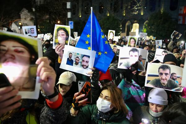 Demonstrators hold portraits of activists injured during protests as they take part in an anti-government rally outside the Parliament building in Tbilisi, Georgia, on Saturday, Dec. 14, 2024. (AP Photo/Zurab Tsertsvadze)