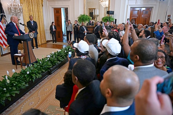 President Donald Trump speaks as golfer Tiger Woods listens during a reception for Black History Month in the East Room of the White House, Thursday, Feb. 20, 2025, in Washington. (Pool via AP)