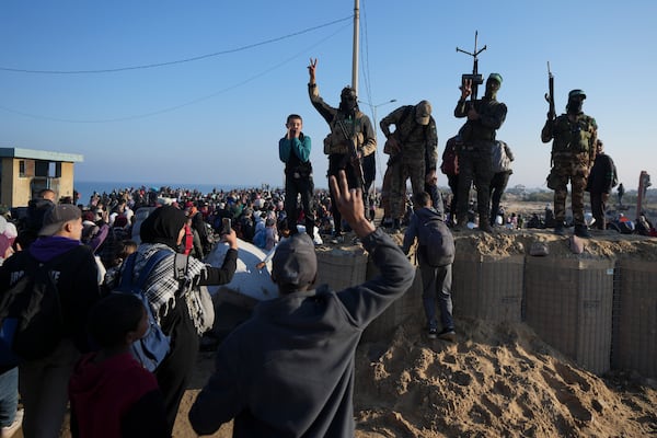 Hamas fighters flash the victory sign as displaced Palestinians return to their homes in the northern Gaza Strip, following Israel's decision to allow thousands of them to go back for the first time since the early weeks of the 15-month war with Hamas, Monday, Jan. 27, 2025. (AP Photo/Abdel Kareem Hana)