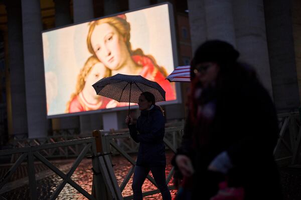 People shelter against the rain as they follow a live broadcasted Rosary prayer for Pope Francis, in St. Peter's Square at the Vatican, Wednesday, March 12, 2025. (AP Photo/Francisco Seco)