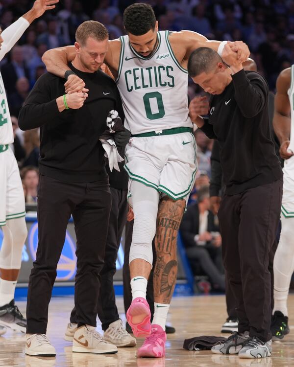 Trainers help Boston Celtics' Jayson Tatum (0) off the court after he was injured during the second half of Game 4 in the Eastern Conference semifinals of the NBA basketball playoffs against the New York Knicks Monday, May 12, 2025, in New York. (AP Photo/Frank Franklin II)