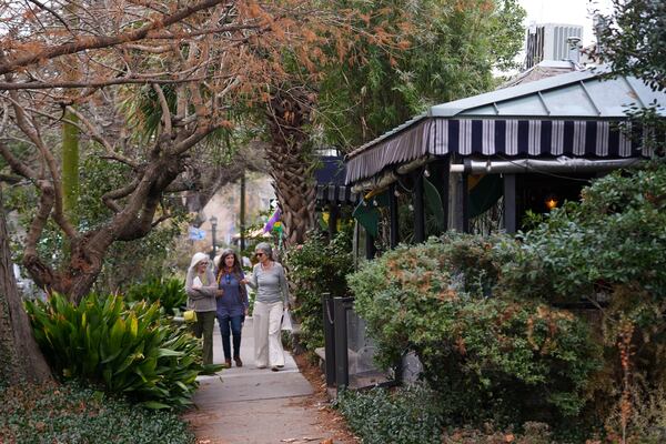 People walk down the sidewalk past Cafe Degas in the largely residential neighborhood of Bayou St. John, near City Park in New Orleans, Wednesday, Jan. 29, 2025. (AP Photo/Gerald Herbert)