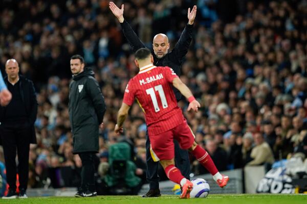 Manchester City's head coach Pep Guardiola, back, gestures as Liverpool's Mohamed Salah reaches the ball during the English Premier League soccer match between Manchester City and Liverpool at Etihad stadium in Manchester, England, Sunday, Feb. 23, 2025. (AP Photo/Dave Thompson)