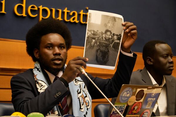 David Yambio, left, flanked by Lam Magok, both from South Sudan, shows a picture of a woman detained in Libyan prison and identified by him as Naima Jamal, during a press conference where they testified their experience in the Libyan prisons, in Rome, Wednesday, Jan. 29, 2025. (AP Photo/Gregorio Borgia)