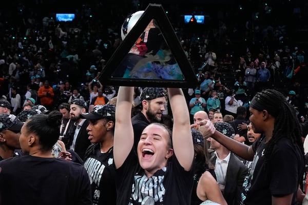 FILE - New York Liberty guard Sabrina Ionescu holds up the championship trophy after the Liberty defeated the Minnesota Lynx in Game 5 of the WNBA basketball final series, Sunday, Oct. 20, 2024, in New York. (AP Photo/Pamela Smith, File)