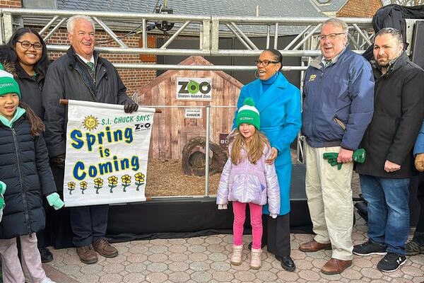 Staten Island District Attorney Michael Mcmahon holds a Spring is Coming sign in front of Staten Island Chuck, the groundhog, whose handlers say has predicted an early spring, at the Staten Island Zoo in New York on Sunday, February 2, 2025. (AP Photo/Ted Shaffrey)