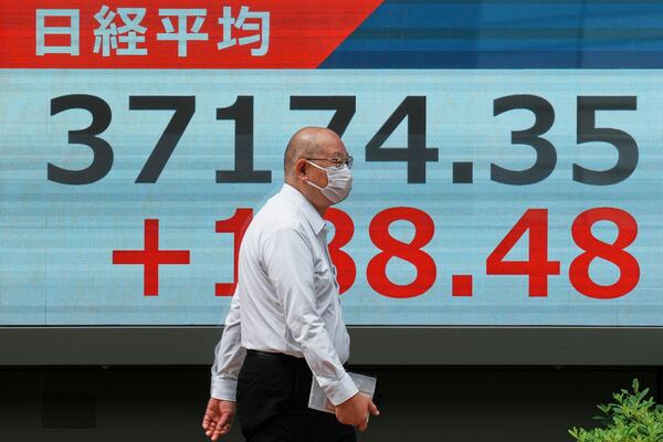 A person walks in front of an electronic stock board showing Japan's Nikkei index at a securities firm Friday, May 23, 2025, in Tokyo. (AP Photo/Eugene Hoshiko)