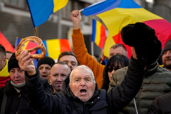 A protester holding a bagel in one hand shouts slogans during a rally organized by the right wing Alliance for the Unity of Romanians (AUR), calling for free elections after Romania' s Constitutional Court annulled the first round of presidential elections last December, in Bucharest, Romania, Sunday, Jan. 12, 2025.(AP Photo/Vadim Ghirda)