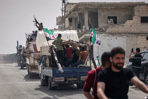 A man fires into the air from one of the trucks carrying some of the 60 displaced families who, supported by an NGO, are returning to their village after more than five years in the Atmeh camps near the Syrian-Turkish border, in Kafr Sijna, south of Idlib, Syria, Sunday, May 18, 2025. (AP Photo/Ghaith Alsayed)