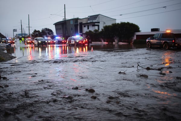 Police monitor a street closure along Pacific Coast Highway in the Palisades Fire zone during a storm Thursday, Feb. 13, 2025, in Malibu, Calif. (AP Photo/Ethan Swope)