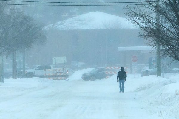 A pedestrian walks along Bay Street on a snowy Wednesday, Feb 12, 2025, in Traverse City, Mich. (Jan-Michael Stump/Traverse City Record-Eagle via AP)