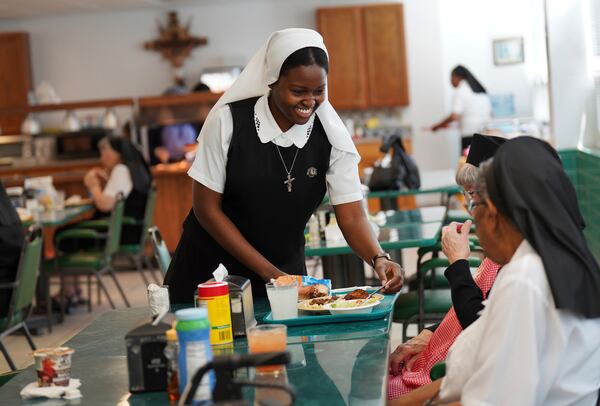 Sister Seyram Mary Adzokpa, of the Sisters of the Holy Family, brings a tray of food to an elderly sister at the motherhouse in New Orleans, Tuesday, June 25, 2024. (AP Photo/Jessie Wardarski)