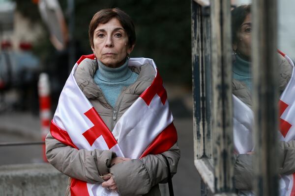 Lika Guntsadze, mother of arrested film and theater actor Andro Chichinadze, drapes herself in a Georgian flag in Tbilisi, Georgia, on Friday, Jan. 31, 2025. (AP Photo/Zurab Tsertsvadze)