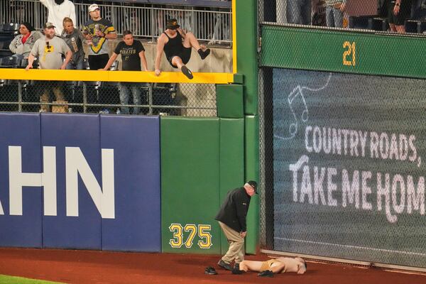 A fan lies on the warning track in right field of PNC Park after falling out of the stands during the seventh inning of a baseball game between the Pittsburgh Pirates and the Chicago Cubs in Pittsburgh, Wednesday, April 30, 2025. (AP Photo/Gene J. Puskar)