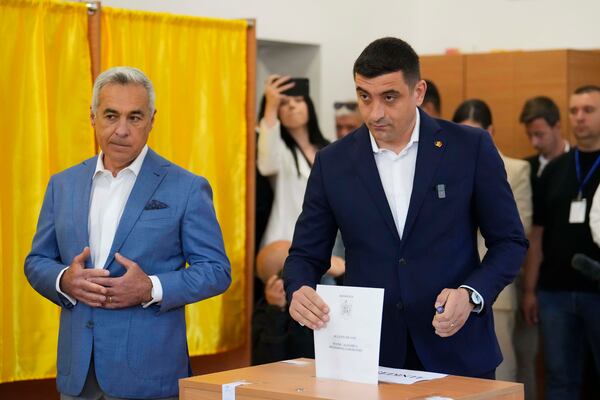 Presidential candidate George Simion, right, casts his vote next to Calin Georgescu, winner of the first round of last year's annulled election, during the first round of the presidential election redo in Bucharest, Romania, Sunday, May 4, 2025. (AP Photo/Vadim Ghirda)