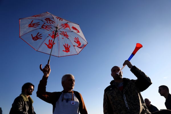 A man holds up an umbrella with painted red hands, a symbol representing the government's bloody hands, during a protest over the collapse of a concrete canopy that killed 15 people more than two months ago, in Novi Sad, Serbia, Saturday, Feb. 1, 2025. (AP Photo/Armin Durgut)