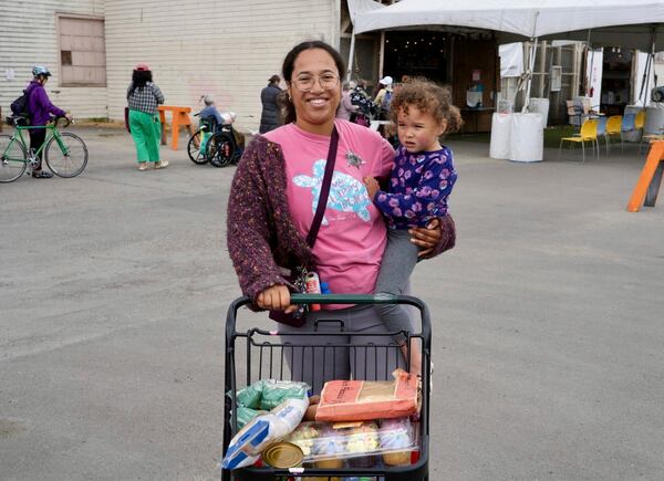 Alameda resident Christina Santamaria stands outside the Alameda Food Bank with groceries and her daughter in Alameda, Calif. on Friday, April 25, 2025. (AP Photo/Terry Chea)